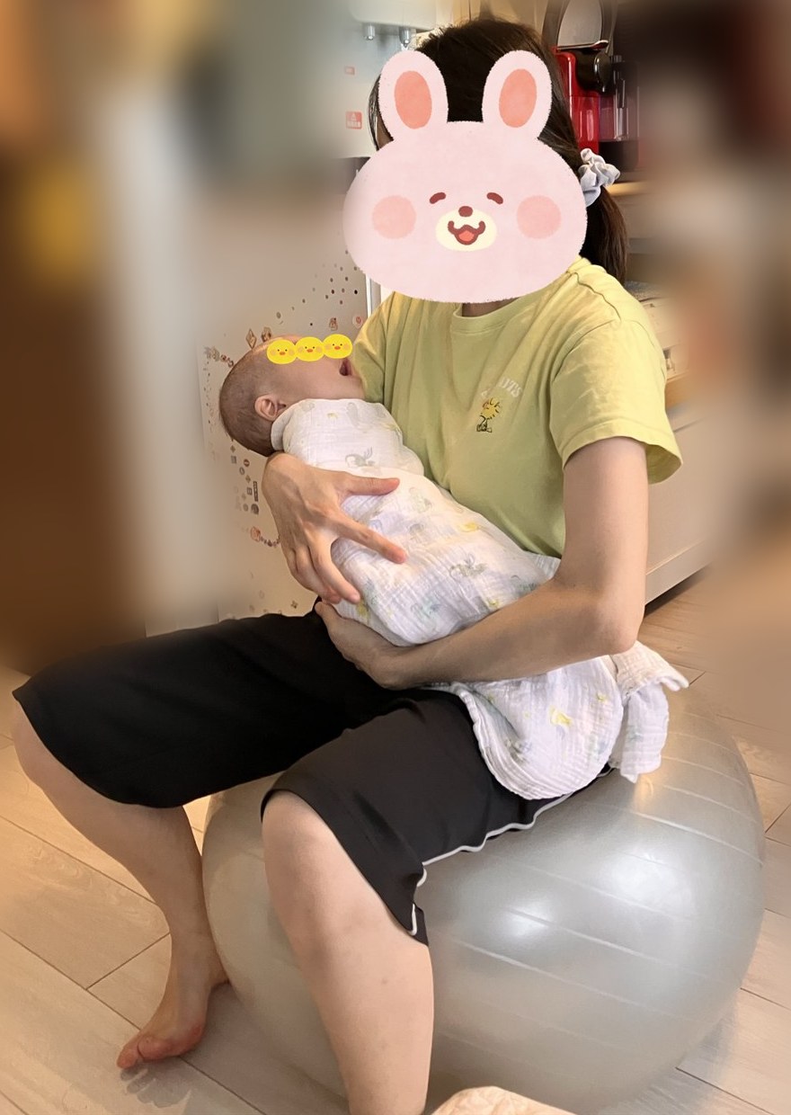 生後3か月の息子をおくるみで抱っこして、バランスボールに座る私