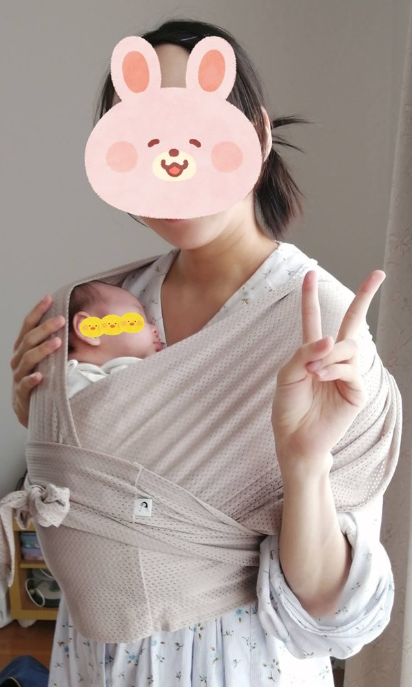 生まれて間もない娘を、コニーの抱っこ紐で抱っこする私(家の中)